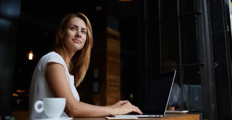 Woman in a cafe with a laptop, staring out the window