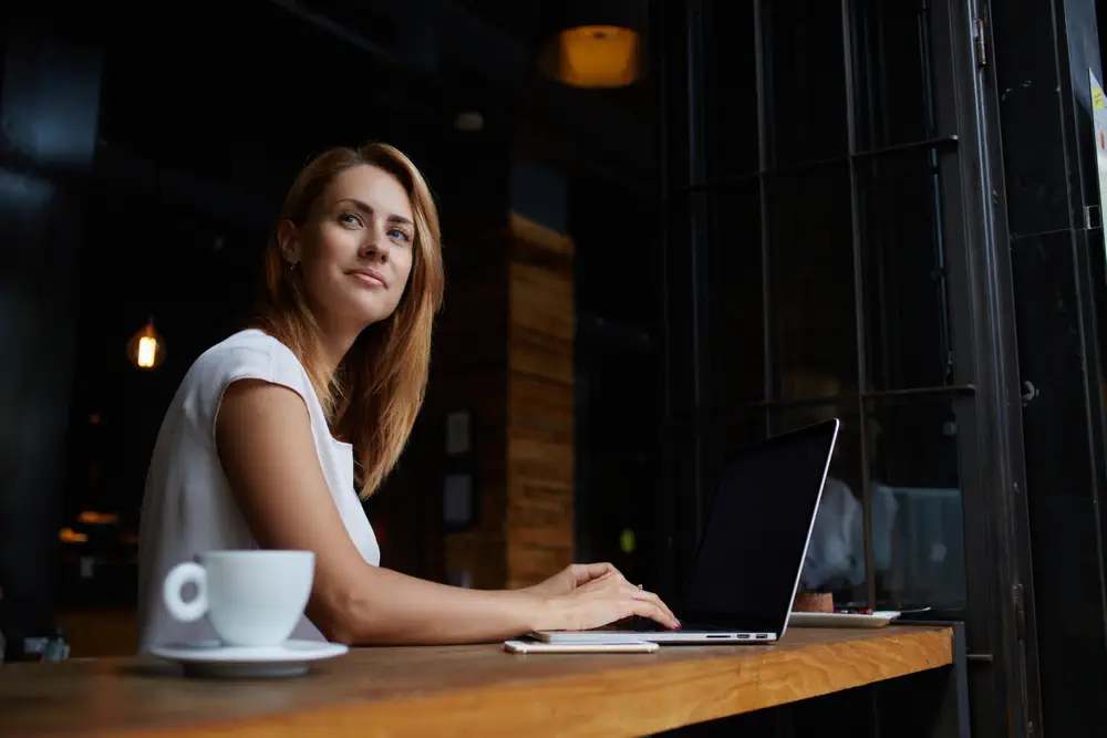 Woman in a cafe with a laptop, staring out the window