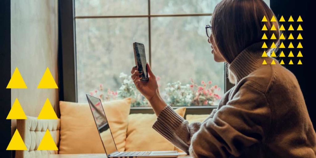 Women looking at phone with laptop