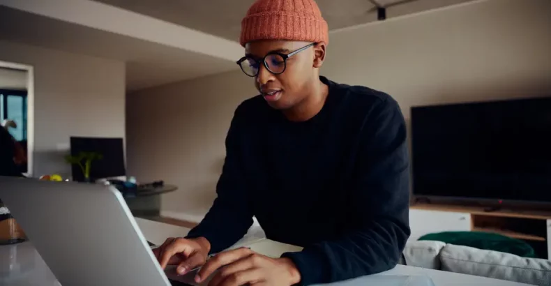 Man looking at laptop with orange beanie on