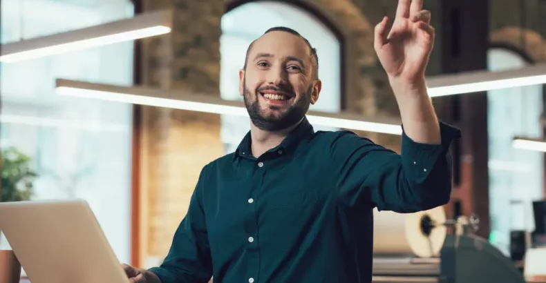 Man with laptop holing his hand up