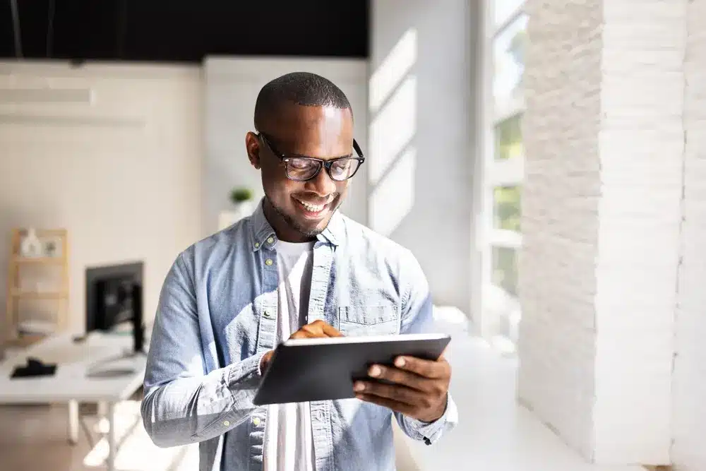 Young man with glasses holding an ipad